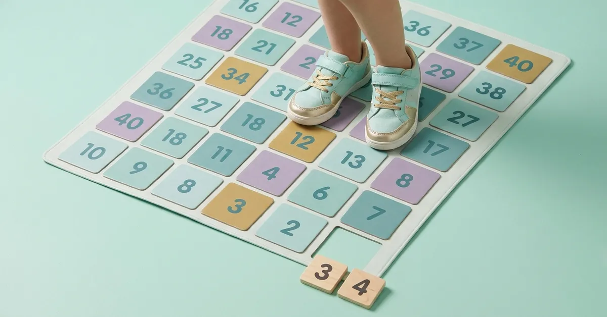 Math made active: child's feet standing on number 12 on a floor grid with 3 x 4 multiplication tiles.